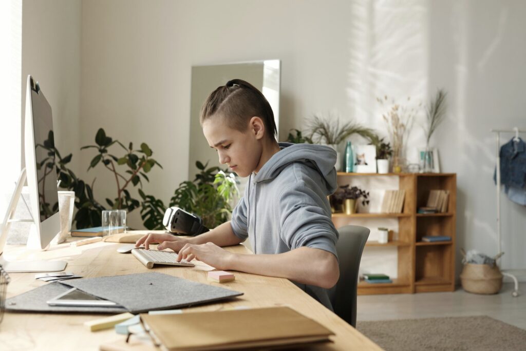 Ung dreng sidder ved skrivebordet derhjemme og arbejder koncentreret