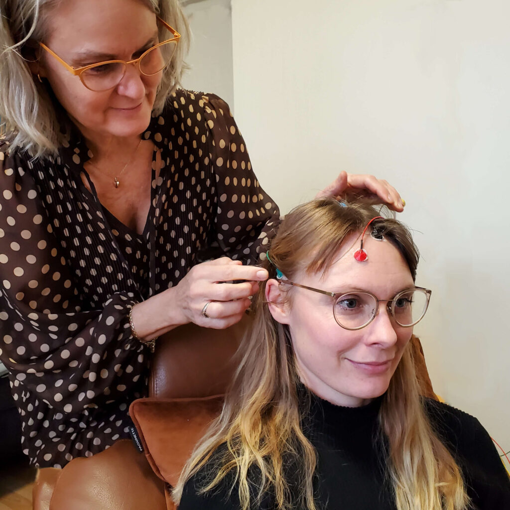 Jette sætter elektroder på en klient før en neurofeedbacksession